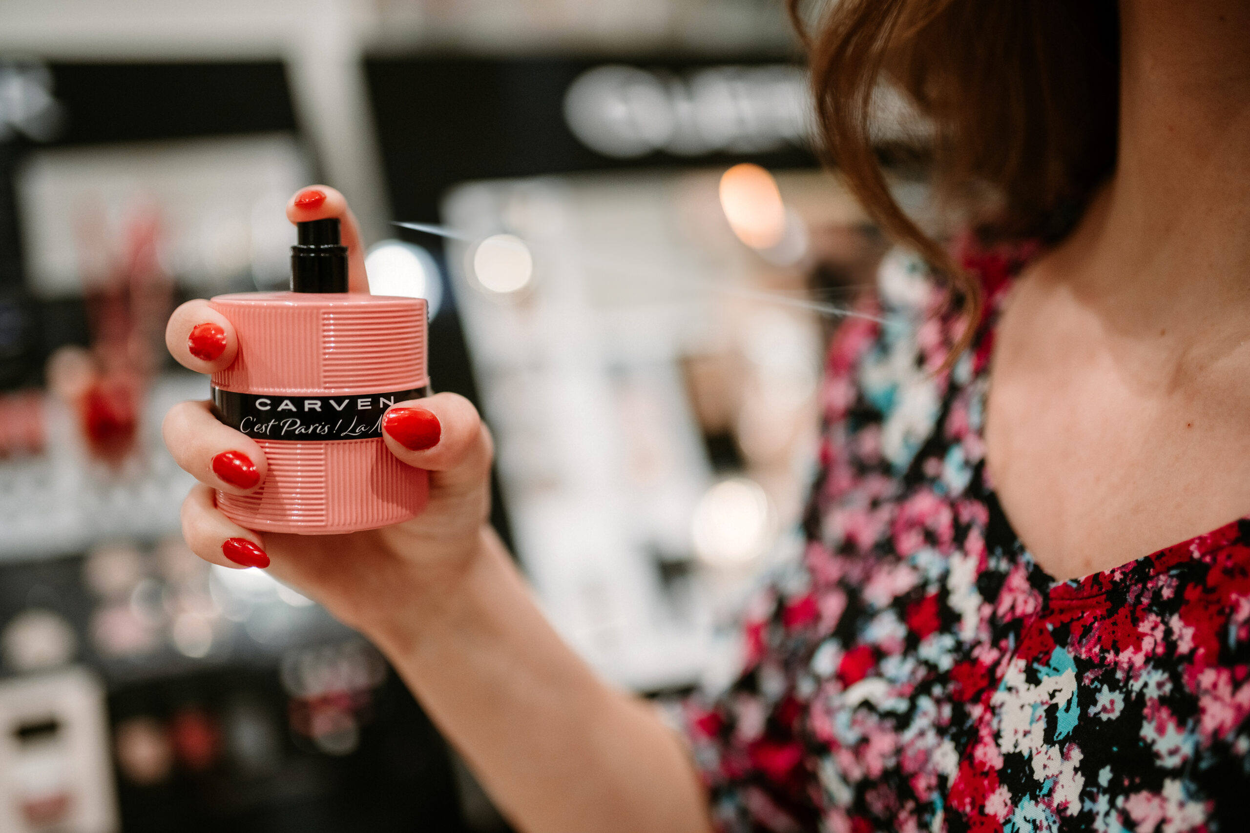 ženská ruka drží ružový parfum Carven